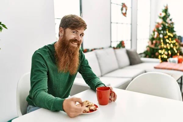 Jonge Roodharige Man Ontbijten Zit Bij Kerstboom Thuis — Stockfoto