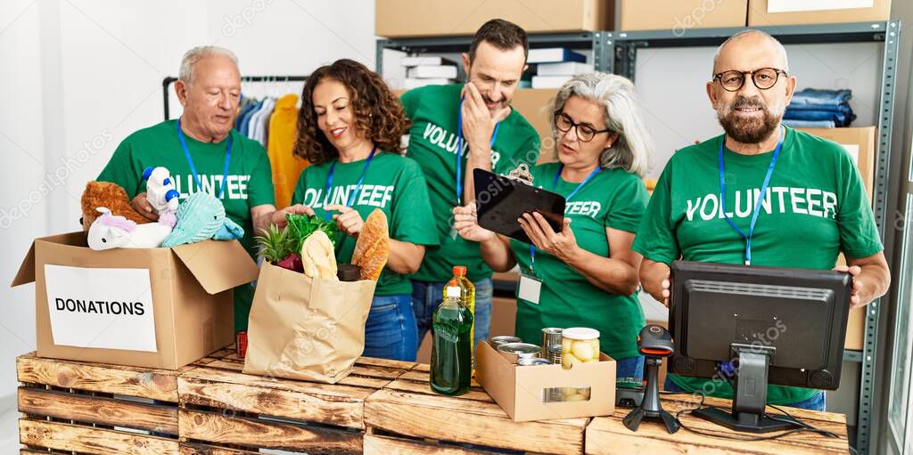 Group of middle age volunteers smiling happy working at charity center.