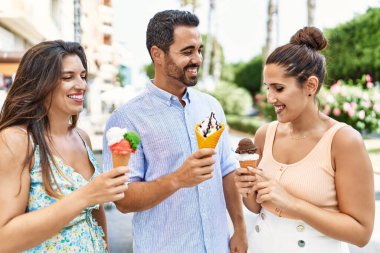 Üç İspanyol arkadaş gülerek şehirde dondurma yiyor..