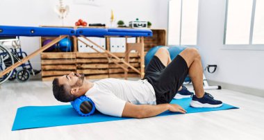 Genç İspanyol hasta klinikte köpük silindir kullanarak boyun rehabilitasyonu seansı yapıyor.