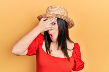 Genç İspanyol kadın yaz şapkası takıyor. Şoka girip yüzünü ve gözlerini kapatıyor. Utanmış ifadesiyle parmaklarından bakıyor.. 