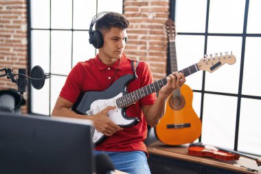 Genç İspanyol müzisyen müzik stüdyosunda elektro gitar çalıyor.