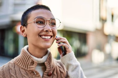 Kısa saçlı, gülümseyen, telefonda konuşan genç İspanyol kadın.