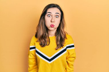 Günlük kıyafetler giyen genç İspanyol kız komik yüzlü yanakları şişiriyor. Havayla şişmiş ağız, çılgın bir ifade.. 