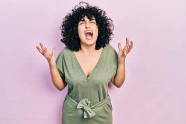 Orta Doğulu genç bir kadın gündelik kıyafetler giyip deli gibi bağırıyor ve agresif bir ifade ve kollarla bağırıyor. hüsran kavramı. 