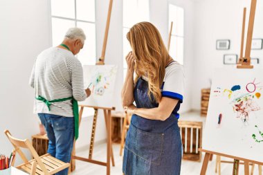 Sanat stüdyosunda önlük giyen İspanyol kadın yorgun, burnu ve gözleri ovuşturup yorgun ve baş ağrısı çekiyor. Stres ve hüsran kavramı. 