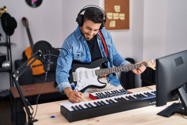 Genç İspanyol adam müzik stüdyosunda elektro gitar çalarak şarkı söylüyor.