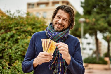 Orta yaşlı yakışıklı bir adam Norveçli kronları parkın dışında tutuyor.