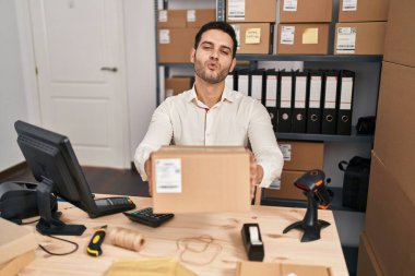 Küçük bir iş yerinde sakallı genç İspanyol bir adam kucağında kameraya bakıp öpüşürken sevimli ve seksi oluyor. aşk ifadesi. 