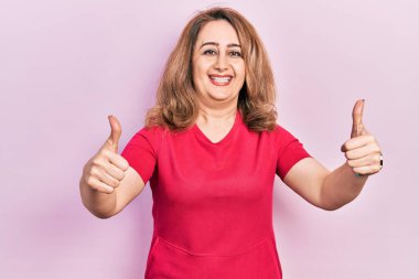 Orta yaşlı beyaz kadın, günlük giysiler giyip, olumlu jestler yapıyor, gülümsüyor ve başarı için seviniyor. kazanan jest. 