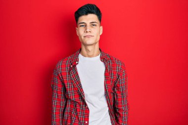 Günlük kıyafetler giyen genç İspanyol adam yüzünde ciddi bir ifadeyle rahatlamış. Basit ve doğal bir şekilde kameraya bakıyorsun.. 