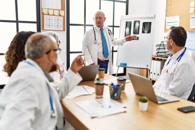 Bir grup orta yaşlı doktor klinikteki bir tıbbi toplantıda tartışıyorlar..