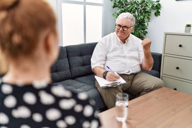 Konsültasyondaki kıdemli psikolog çok mutlu ve heyecanlı bir şekilde kollarını kaldırıp, gülümseyip, başarı için bağırarak kazanan bir jest yapıyor. kutlama konsepti. 