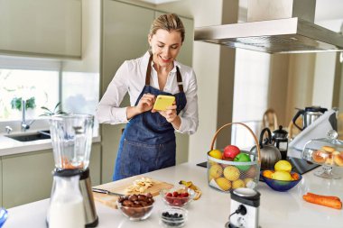 Genç sarışın kadın mutfakta muz dilimleri yapıyor.