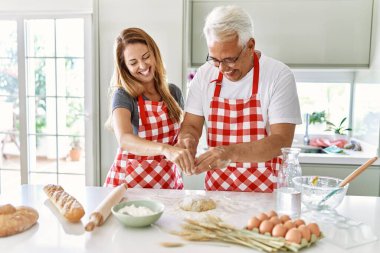 Orta yaşlı İspanyol çift gülümseyerek mutfakta mutlu ekmek pişiriyor..