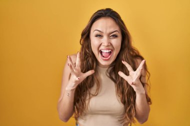 Sarı arka planda duran genç İspanyol kadın çılgın ve başarıyı kollarını kaldırıp heyecanla haykırarak kutluyor. Kazanan konsept 