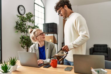 İşadamı ofisteki iş arkadaşına kahve dolduruyor.