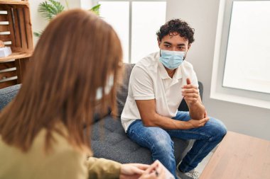 Man and woman wearing medical mask having psychology session at psychology center