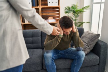 Kadın ve erkek klinikte elleri kulaklarında psikoloji seansı yapıyorlar.