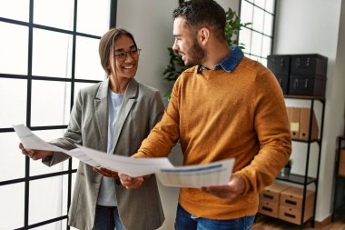 Ofiste bekleyen iki işadamı mutlu bir şekilde evrak okuyorlar..