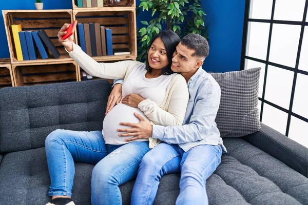 一对年轻的拉丁夫妇期待着宝宝在家用智能手机自拍 — 图库照片