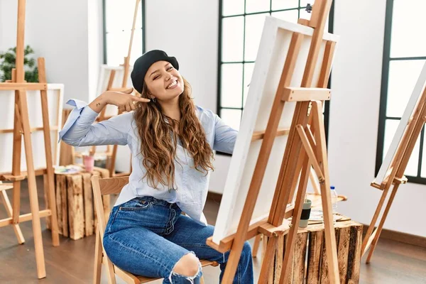 若いヒスパニック系のアーティストの女性は アートスタジオでのキャンバス上の絵は陽気な表情と指の歯と口で指して笑顔 歯の健康の概念 — ストック写真