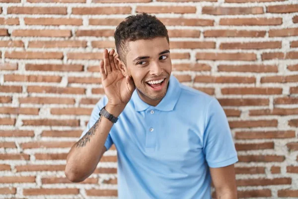 Brazylijski Młodzieniec Stojący Nad Murem Uśmiechający Się Ręki Ucho Słuchający — Zdjęcie stockowe