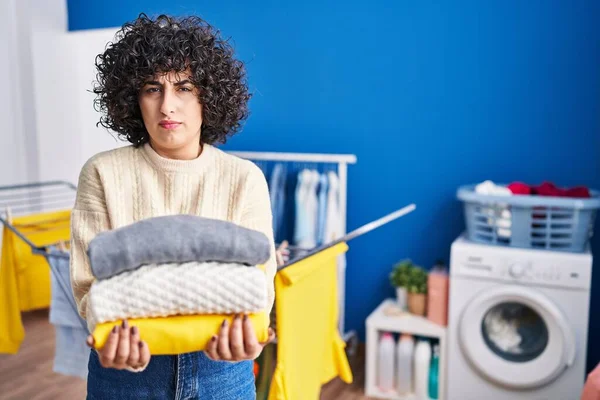 Young Brunette Woman Curly Hair Holding Clean Laundry Skeptic Nervous — Foto de Stock