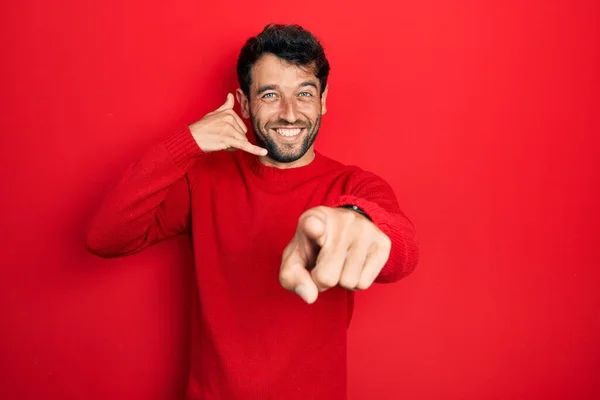 Pohledný Muž Vousy Neformálním Červeném Svetru Usmívá Mluví Telefonu Ukazuje — Stock fotografie