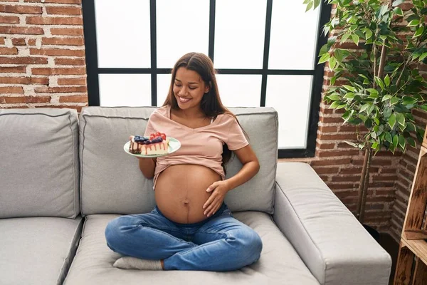 Young Latin Woman Pregnant Eating Sweets Sitting Sofa Home — Foto de Stock