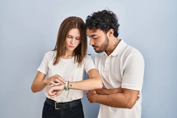 Young Couple Wearing Casual Clothes Standing Together Checking Time Wrist —  Fotos de Stock