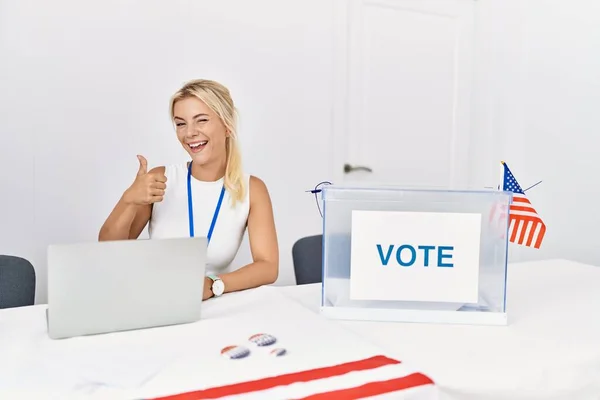 Young caucasian woman at america political campaign election doing happy thumbs up gesture with hand. approving expression looking at the camera showing success.