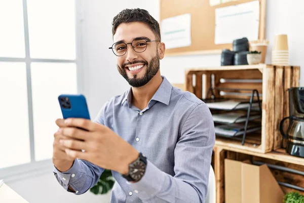 Young arab man smiling confident using smartphone working at office