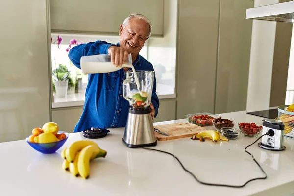 Hombre Mayor Sonriendo Confiado Vertiendo Leche Licuadora Cocina —  Fotos de Stock