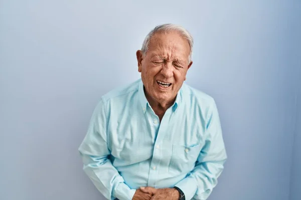 Starší Muž Šedými Vlasy Stojící Nad Modrým Pozadím Rukou Břiše — Stock fotografie