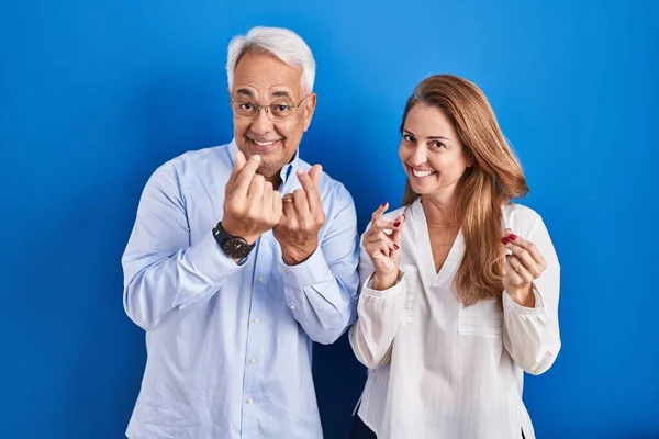 Middle Age Hispanic Couple Standing Blue Background Doing Money Gesture — Stockfoto