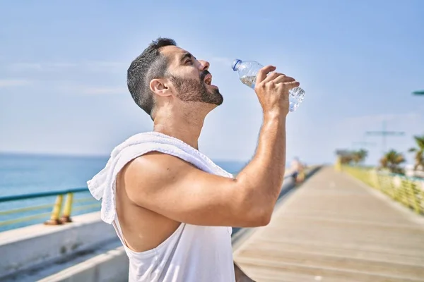 晴れた日に屋外で水分補給を維持するために運動スタイルの飲料水を身に着けているヒスパニック系スポーツマン — ストック写真