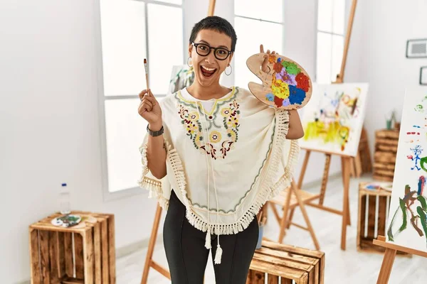 年轻的惊慌失措的女人微笑着 自信地拿着画笔和调色板在艺术工作室里 — 图库照片
