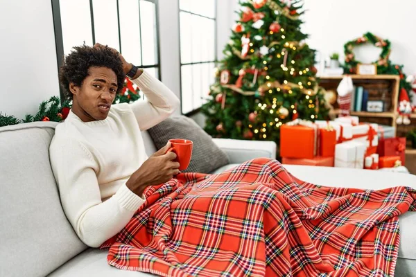 Joven Afroamericano Sentado Sofá Bebiendo Café Junto Árbol Navidad Confunde — Foto de Stock
