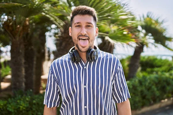Young Handsome Man Listening Music Using Headphones Outdoors Sticking Tongue — Foto Stock