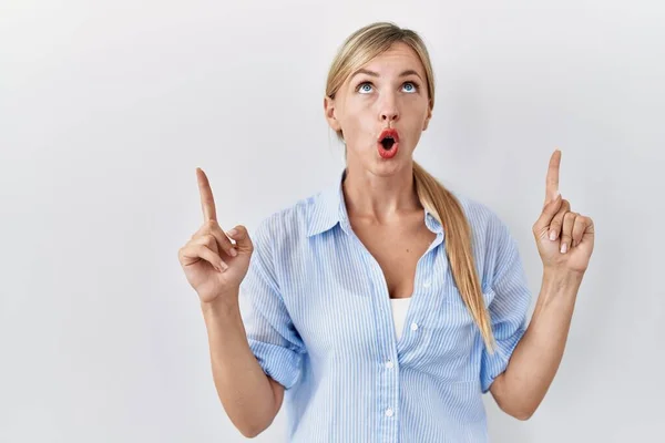 Beautiful Blonde Woman Standing White Background Amazed Surprised Looking Pointing — Stock fotografie