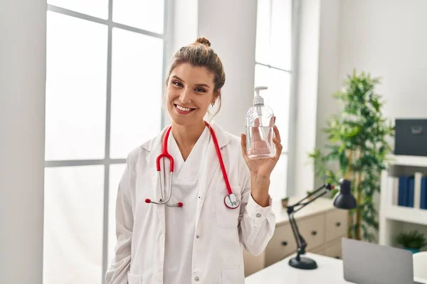 Jovem Loira Vestindo Uniforme Médico Segurando Mãos Gel Desinfetante Clínica — Fotografia de Stock