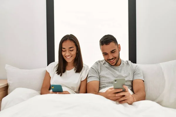 Genç Latin Çift Evde Yatarken Akıllı Telefon Kullanıyor — Stok fotoğraf
