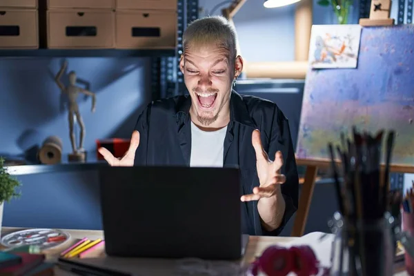 Young Caucasian Man Using Laptop Night Art Studio Celebrating Crazy — Stock Photo, Image