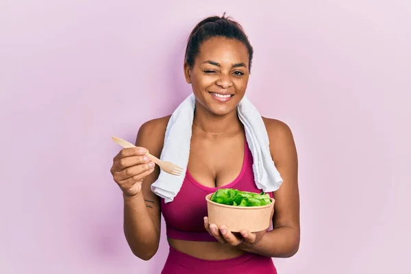 Young African American Girl Wearing Sportswear Eating Salad Winking Looking — Photo