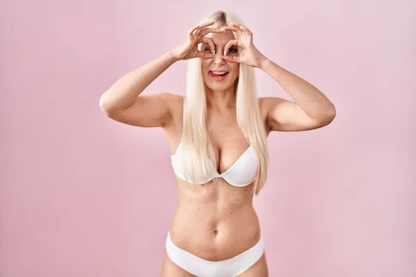 Caucasian Woman Wearing Lingerie Pink Background Doing Gesture Binoculars Sticking — Stockfoto