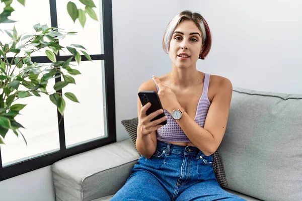 Young Beautiful Woman Using Smartphone Typing Message Sitting Sofa Pointing — Fotografia de Stock