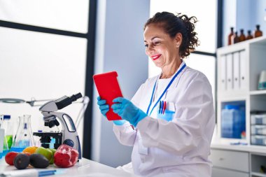 Laboratuvarda tabletle çalışan orta yaşlı İspanyol kadın.