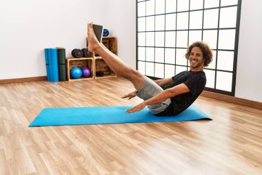 Genç İspanyol sporcu gülümseyerek spor merkezinde mutlu bir antrenman yapıyor..