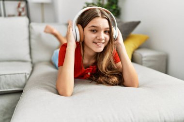 Evdeki kanepede uzanmış müzik dinleyen sevimli kız.
